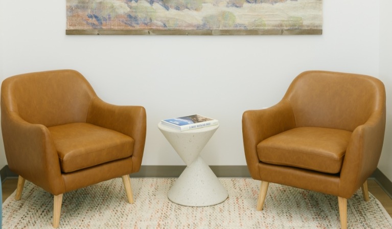 Two brown leather armchairs with small table between them